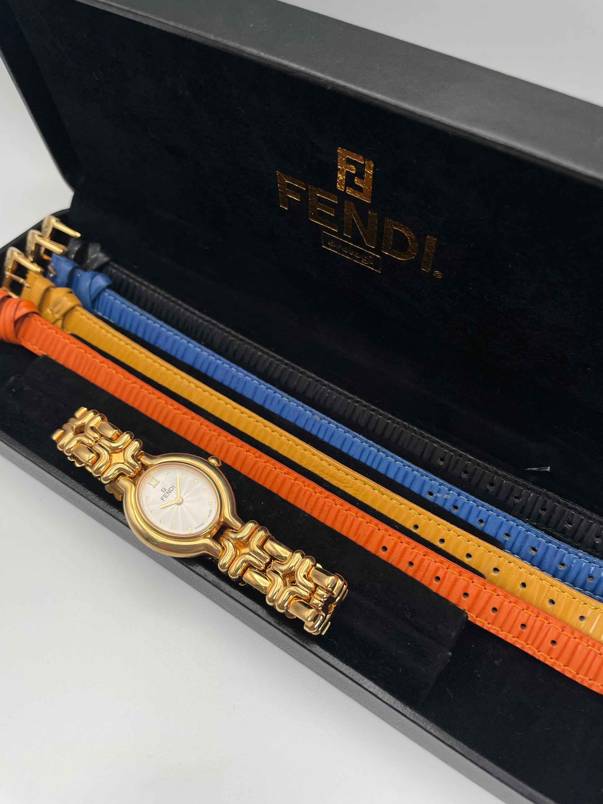 Fendi 640L Vintage Women's Watch, featuring a gold-tone oval case and a white guilloché dial, paired with a unique sculptural link bracelet, shown with its box and 4 replaceable straps.