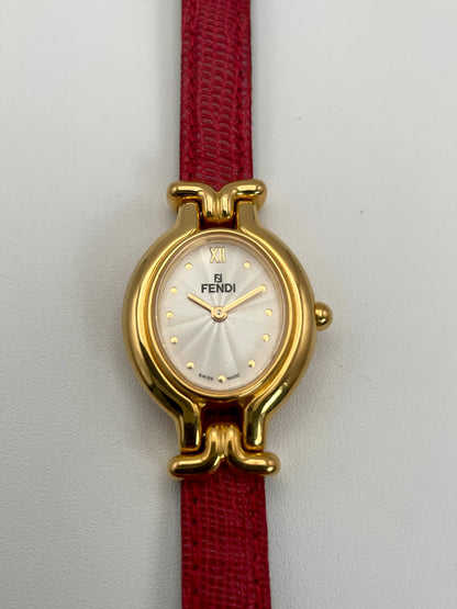 Front view of the Fendi 640L gold watch featuring a white guilloché dial and red leather strap.