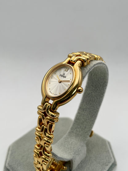 Side angle view of the Fendi 640L Vintage Women's Watch, featuring a gold-tone oval case and a white guilloché dial, paired with a unique sculptural link bracelet.