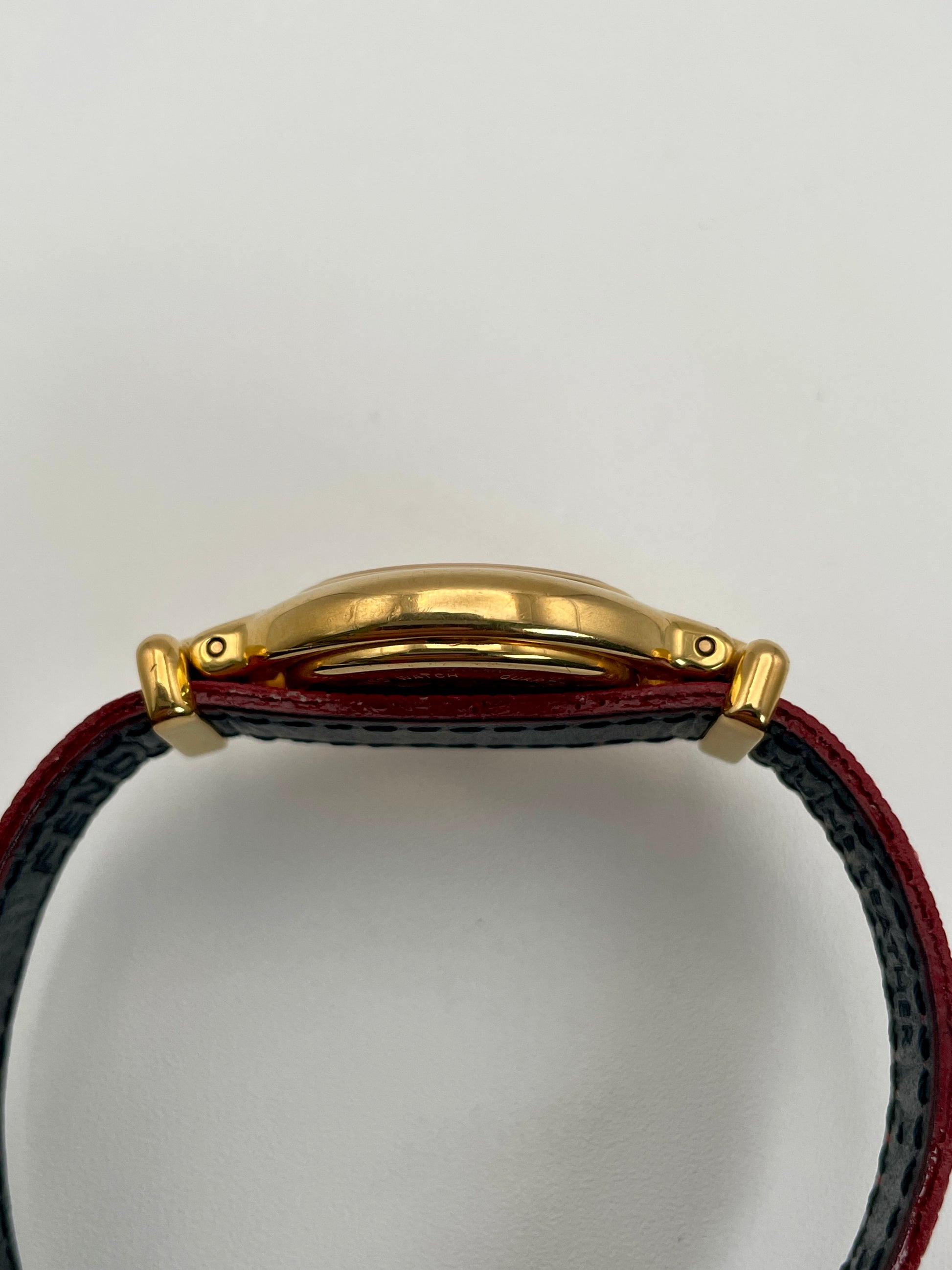 Side profile of the Fendi 640L gold watch with a slim case design and red leather strap.