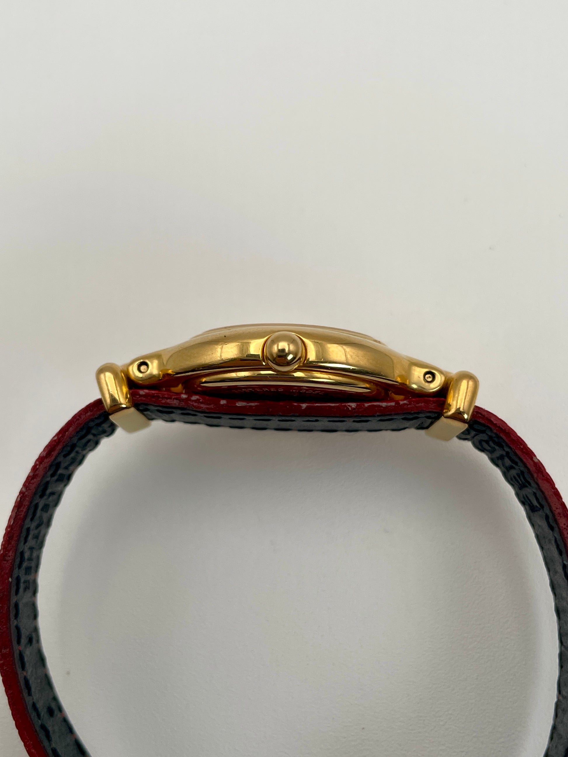 Side profile of the Fendi 640L gold watch with a slim case design and red leather strap.