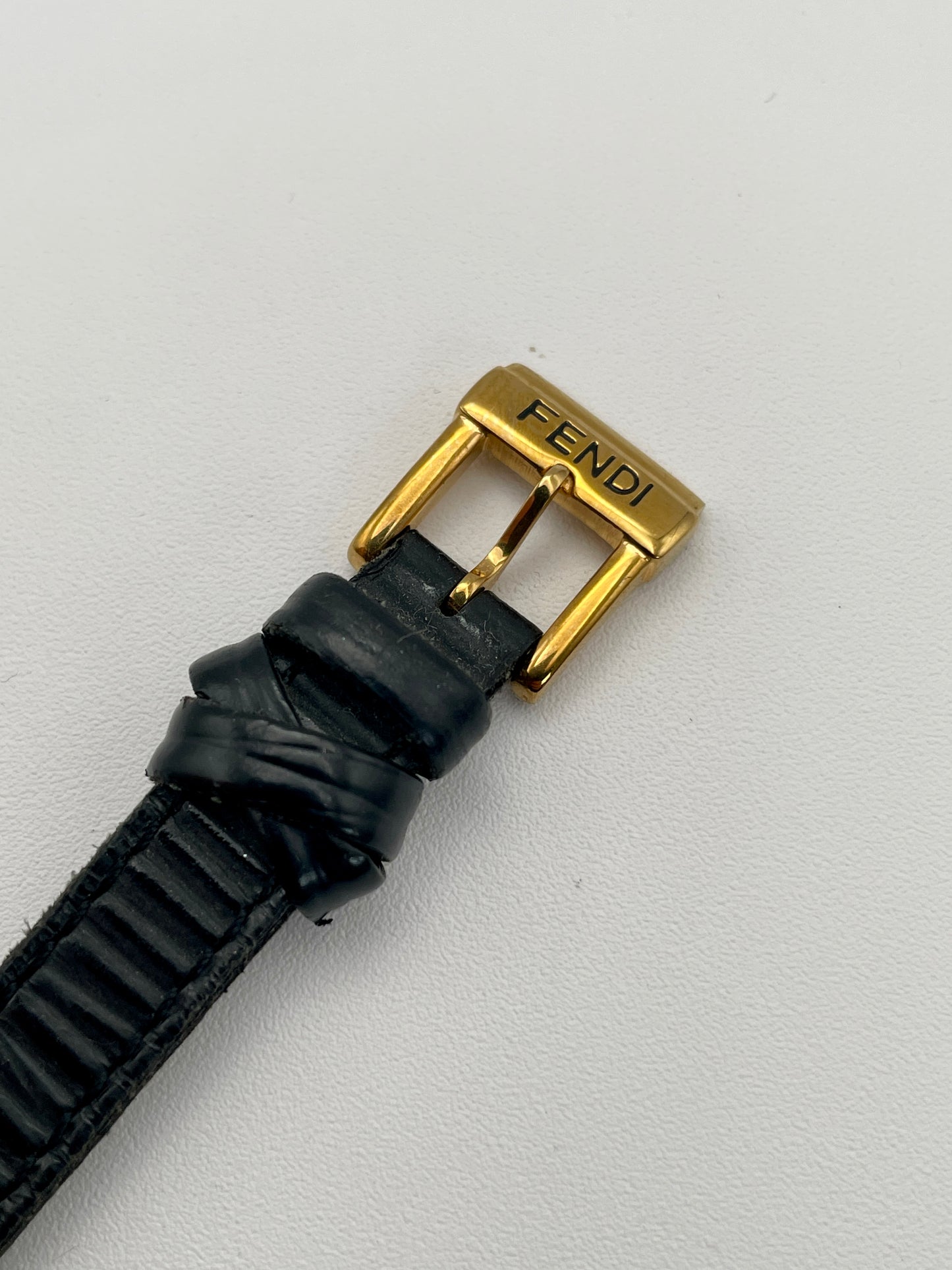 Close-up view of the Fendi 640L watch's gold buckle on a black leather strap.