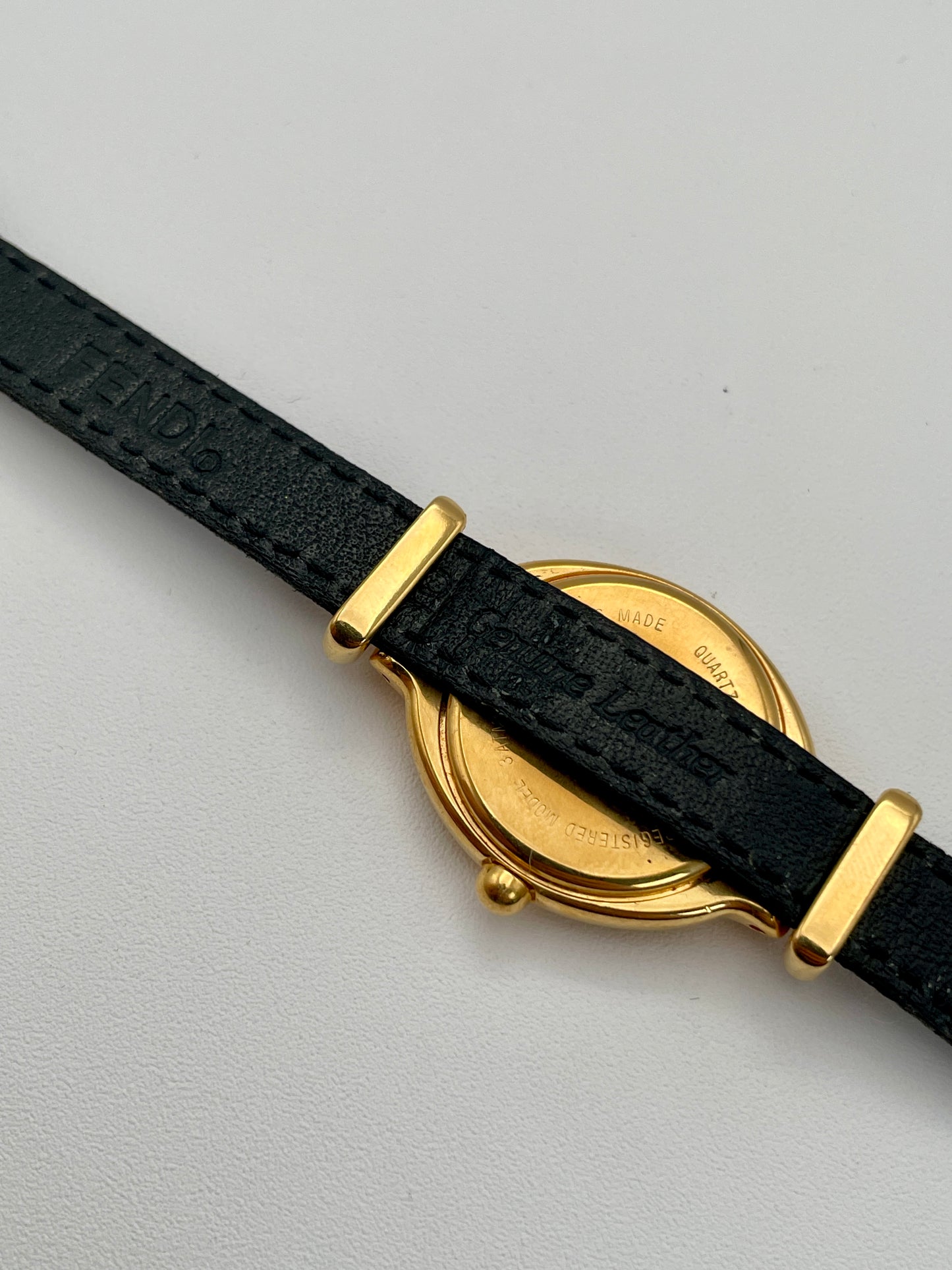 Caseback view of Fendi 640L watch, showcasing the gold case and black leather strap.