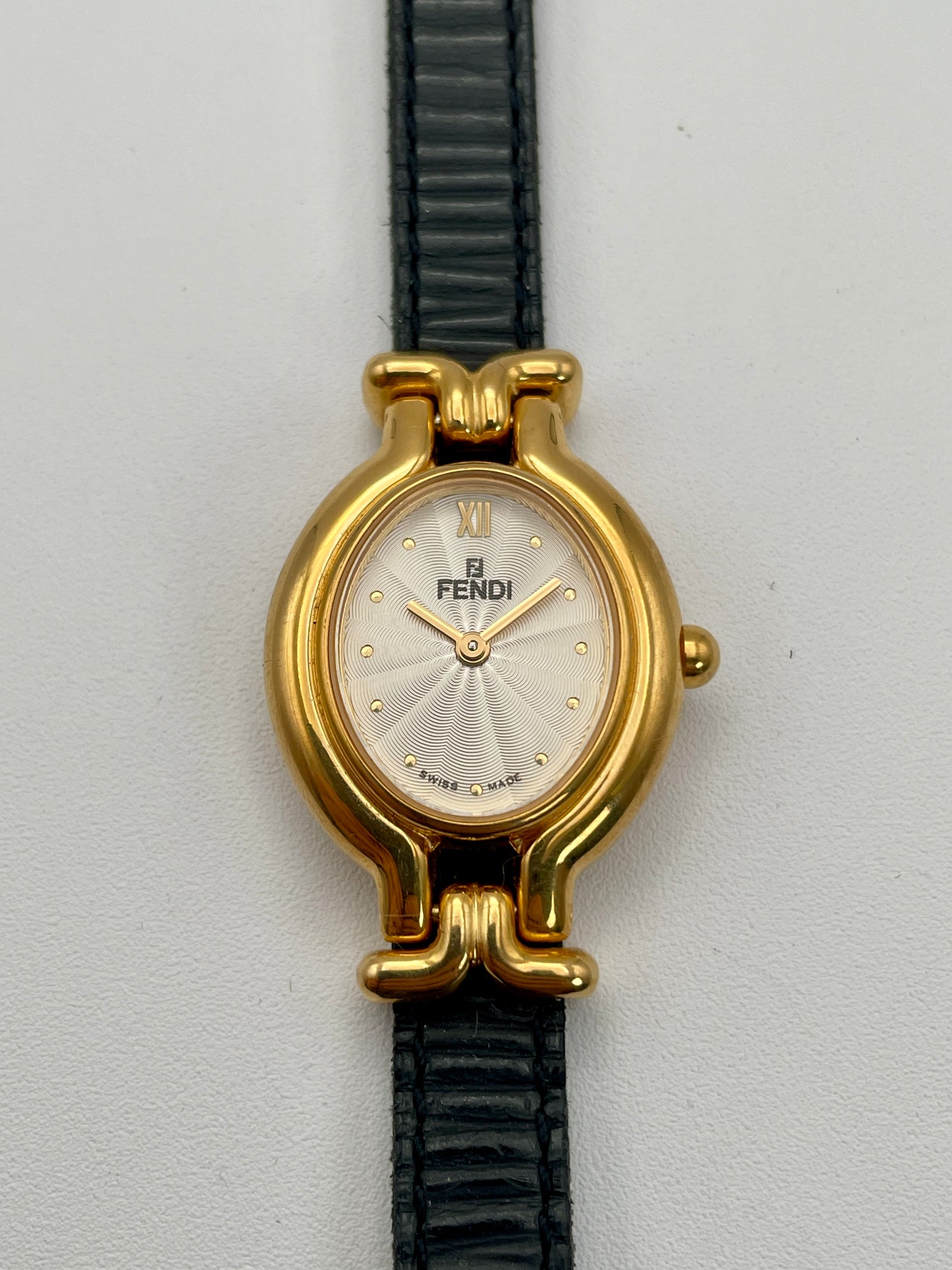 Front view of Fendi 640L watch with gold case, white dial, and black leather strap.