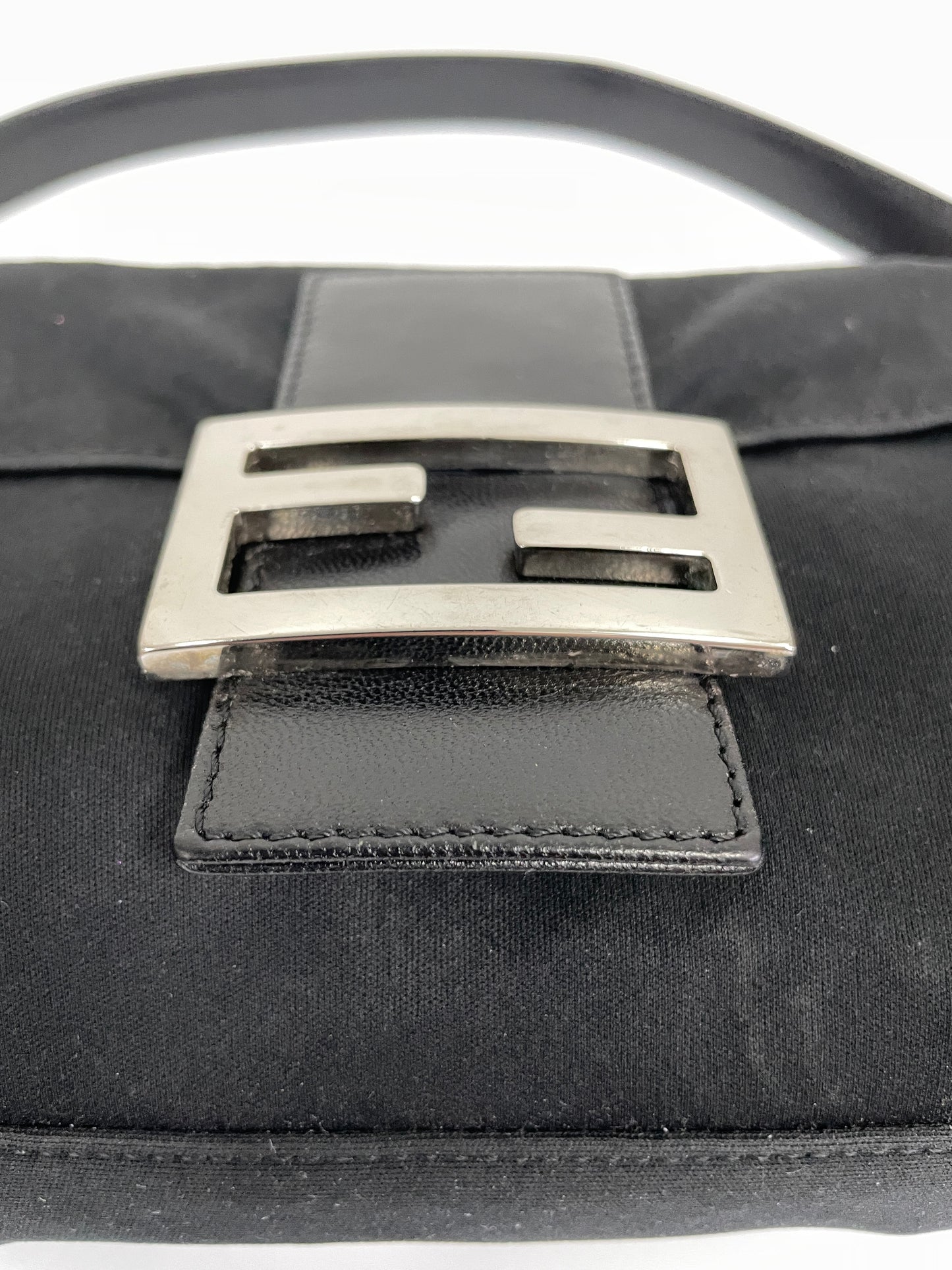 Close-up of the silver Fendi buckle on the black neoprene Fendi Baguette Bag.