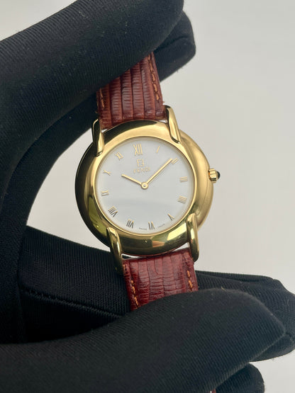 Close-up of the Fendi Orologi 410G vintage watch showing its gold case, white dial, and Roman numeral markers.