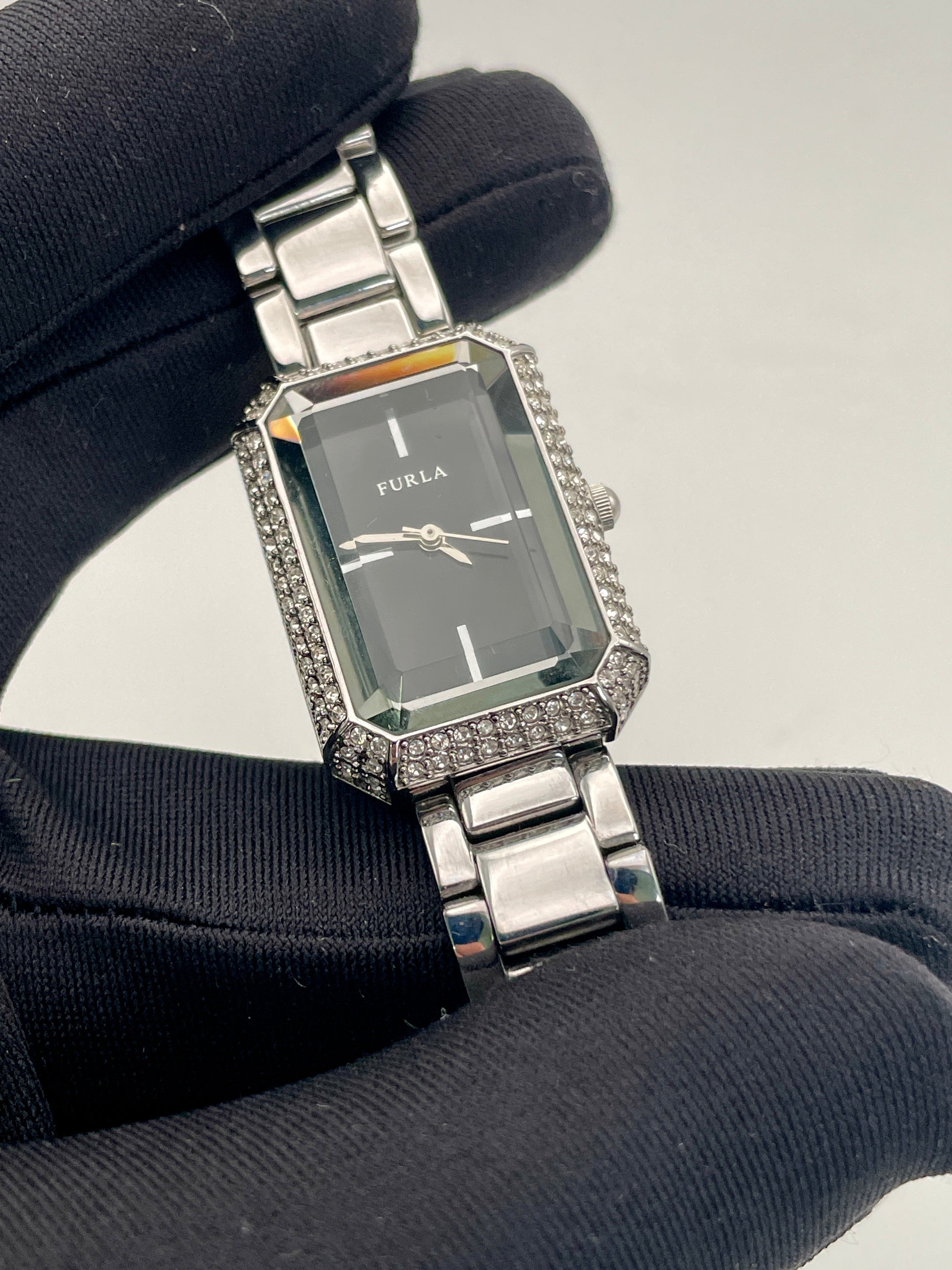 Close-up view of Furla Crystal Pave watch held in a hand, highlighting the crystal-encrusted rectangular case and black dial.