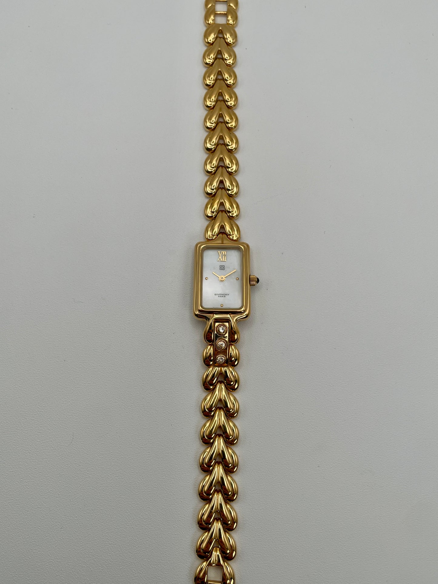 Flatlay of the Givenchy Bambou gold watch showing the full bracelet and dial facing up