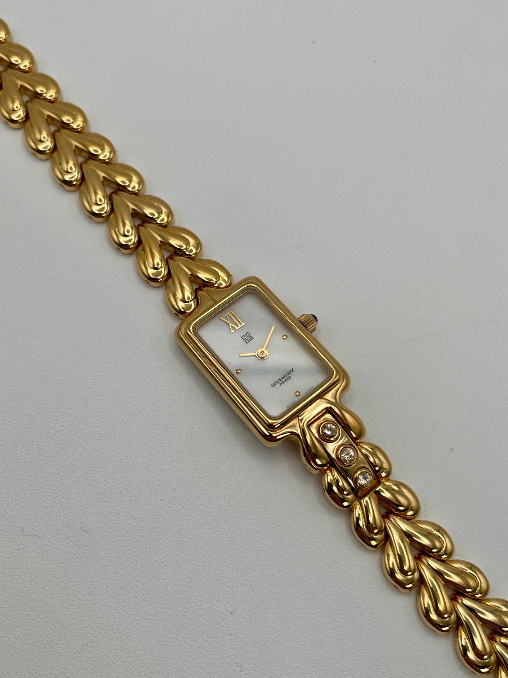 Flatlay of the Givenchy Bambou gold watch showing the full bracelet and dial facing up