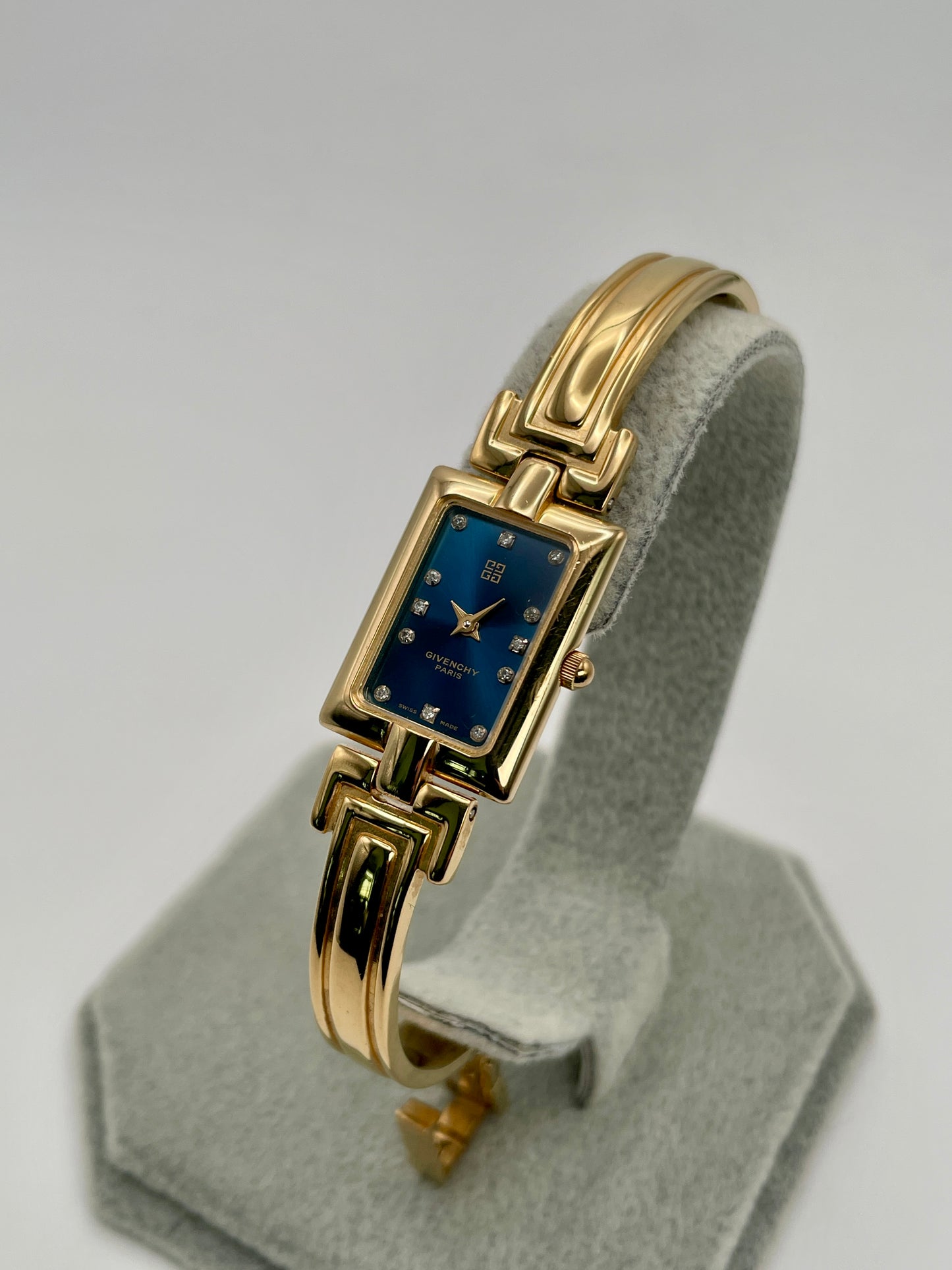 Diagonal view highlighting the right side of the gold bangle and deep blue Givenchy dial