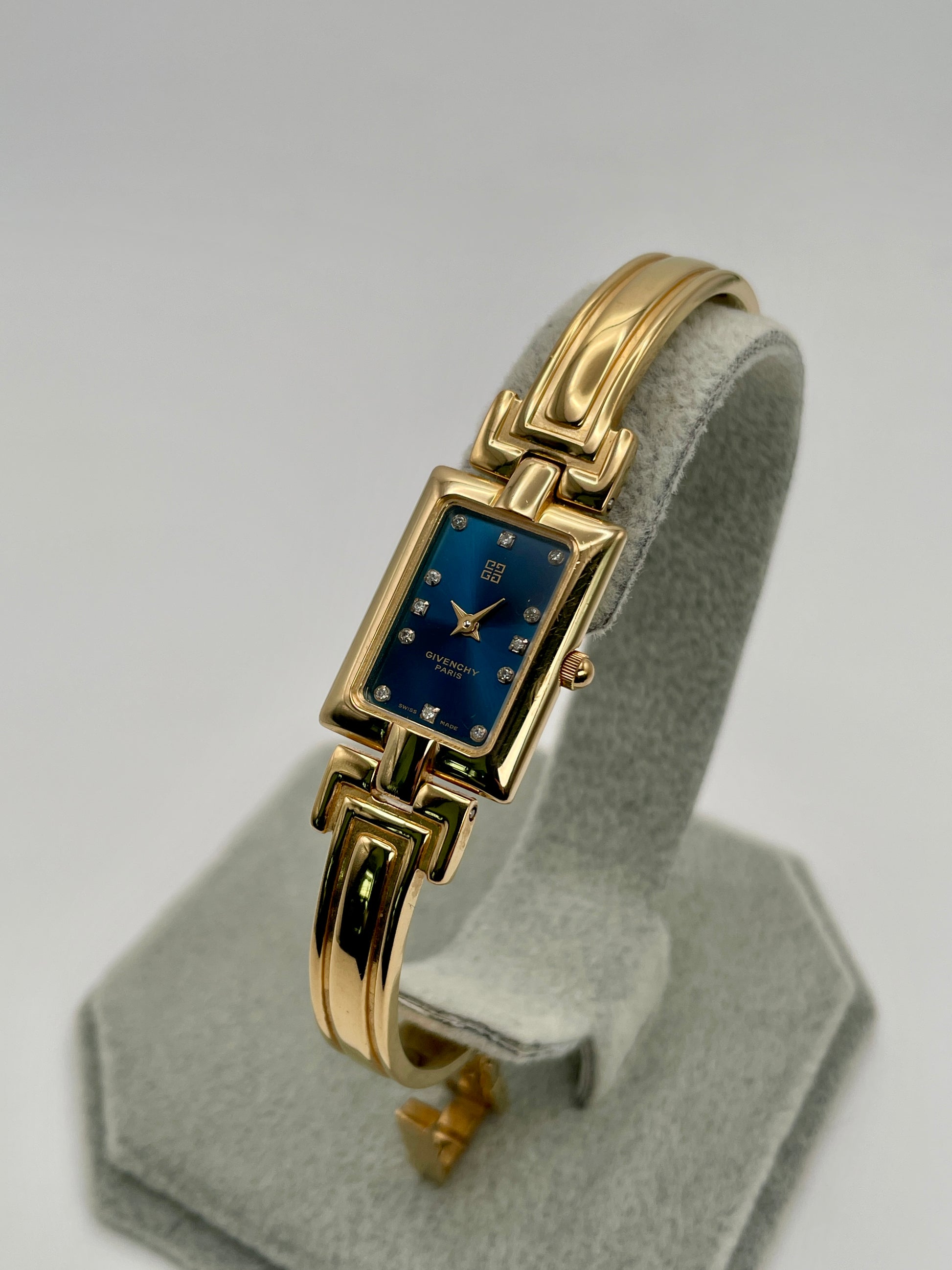 Diagonal view highlighting the right side of the gold bangle and deep blue Givenchy dial