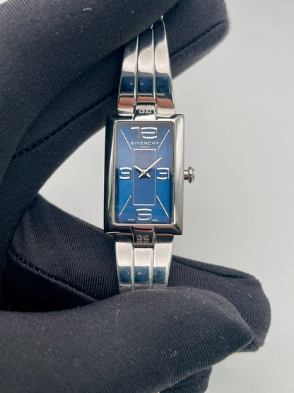 Close-up handheld view of the Givenchy Tank watch showing bold dial and silver bracelet
