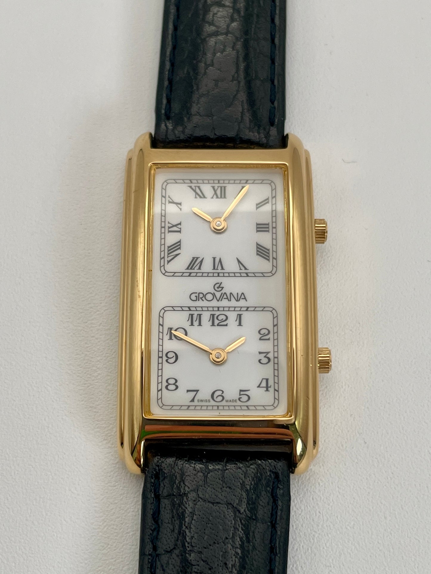 Front view of Grovana Tank Dual Time watch with a gold-tone rectangular case, white dual dials, and black leather strap.