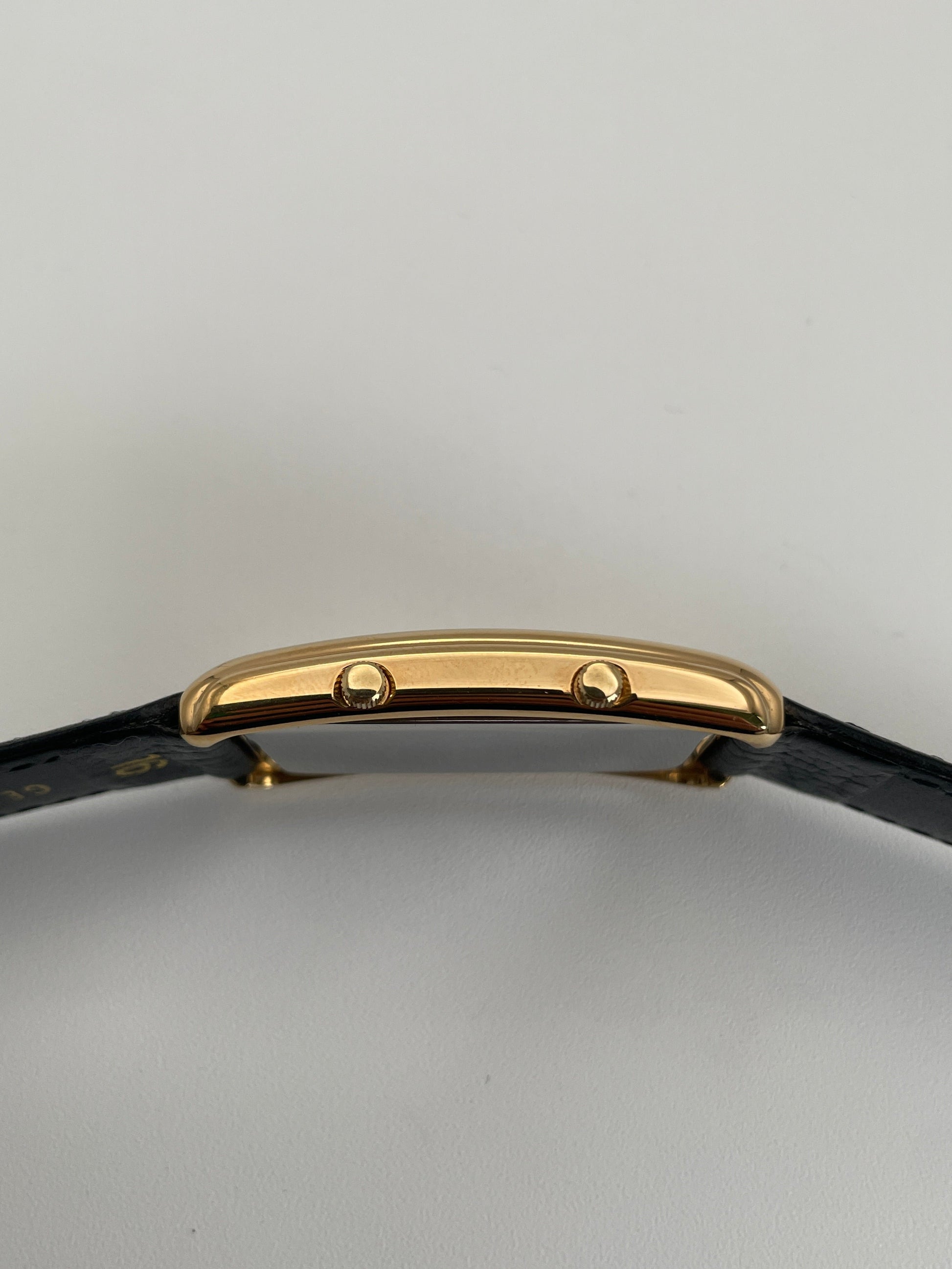 Side crown view of Grovana Tank Dual Time watch featuring a gold-tone rectangular case and black leather strap.