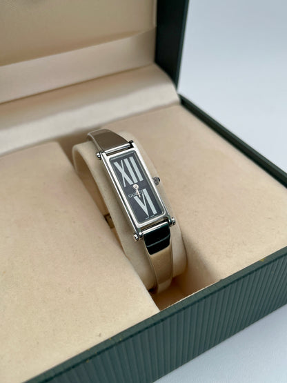 Gucci 1500L black dial watch with a rectangular silver-tone case and stainless steel bracelet, displayed in the original Gucci box.