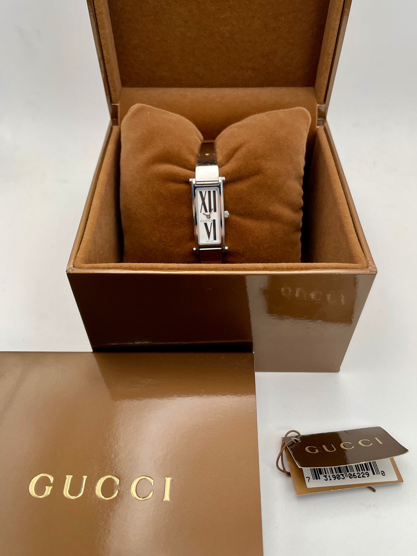 Gucci 1500L white dial watch with a rectangular silver-tone case and stainless steel bracelet, displayed in the original Gucci box with original papers and tags.