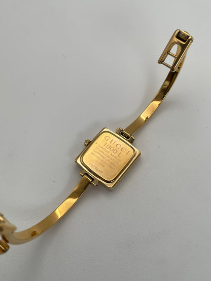 Caseback view of Gucci 1900L gold watch showing the engraved details and gold bangle bracelet.