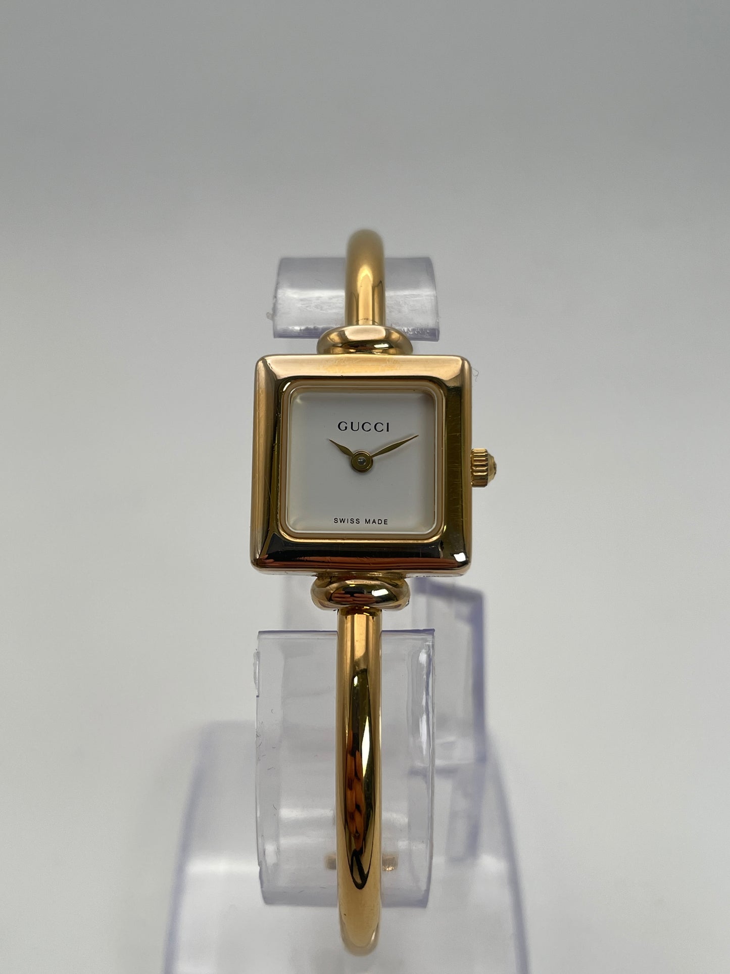 Front view of Gucci 1900L gold watch with a square case and white dial, featuring a gold bangle bracelet.