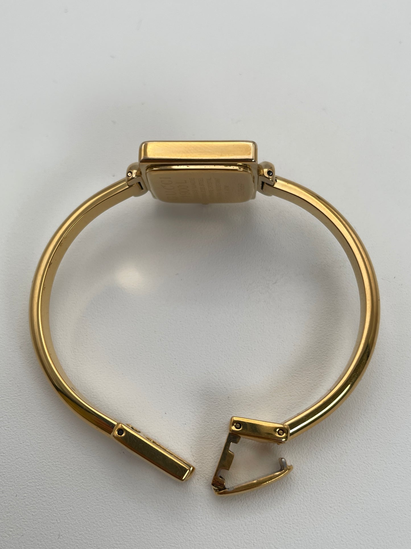 Side view of Gucci 1900L gold watch showing the gold bangle bracelet and square case.