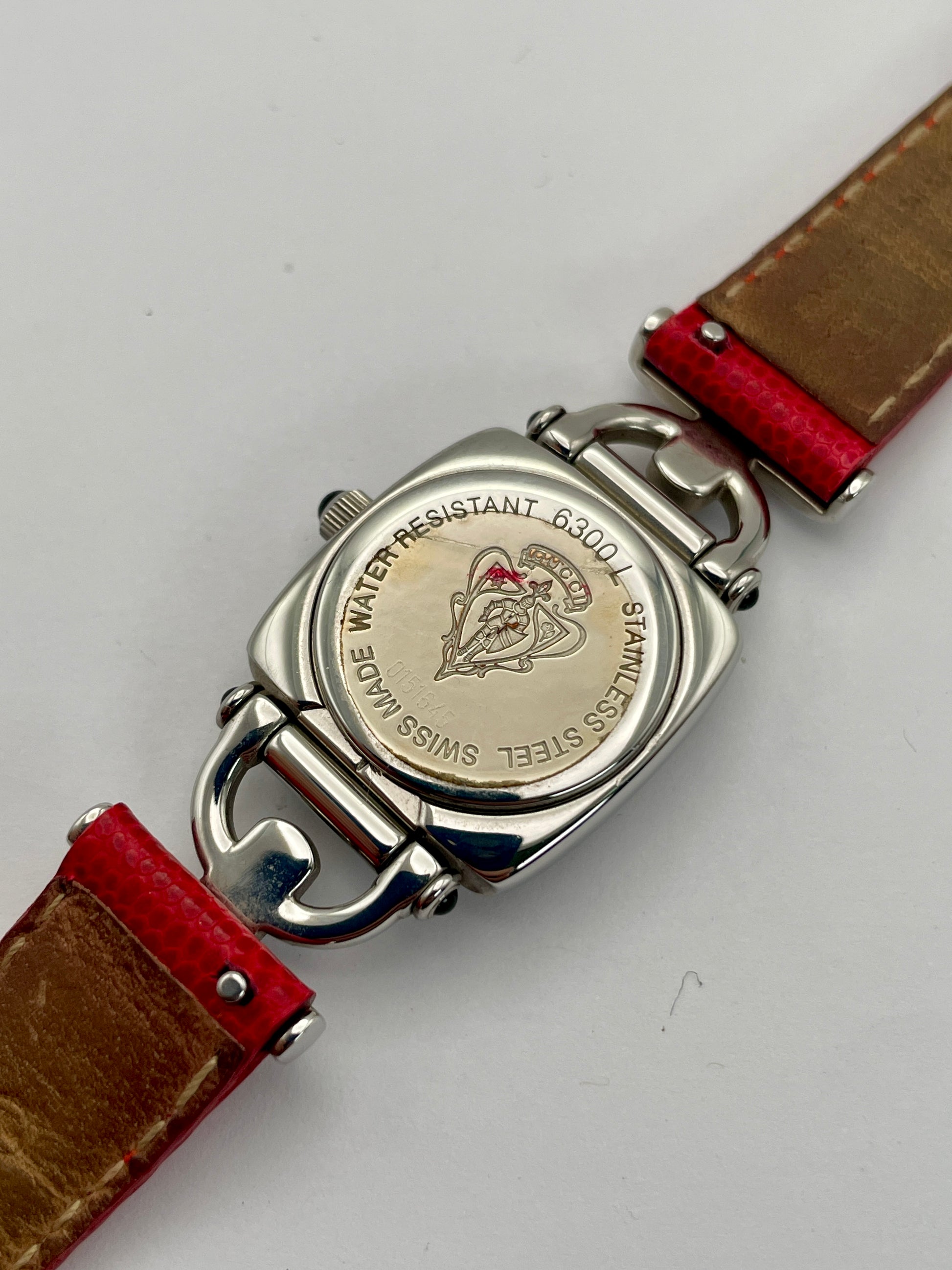 Caseback view of a Gucci 6300L ladies' watch with an engraved stainless steel back, detailing the model number and water resistance.
