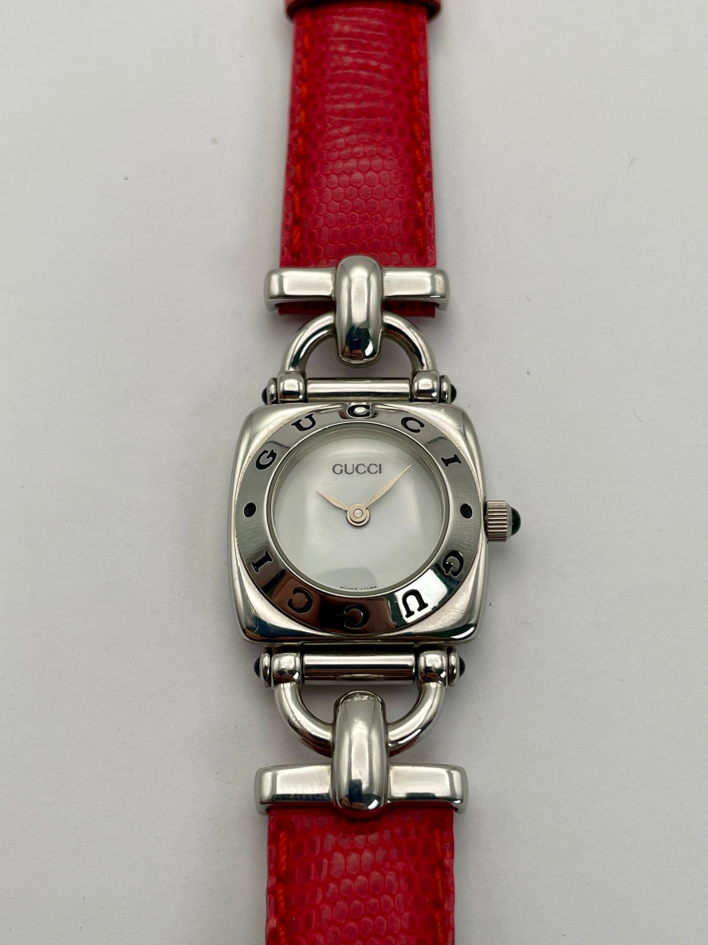 Front view of a Gucci 6300L ladies' watch featuring a stainless steel square case with rounded edges, white dial, and red lizard skin strap.