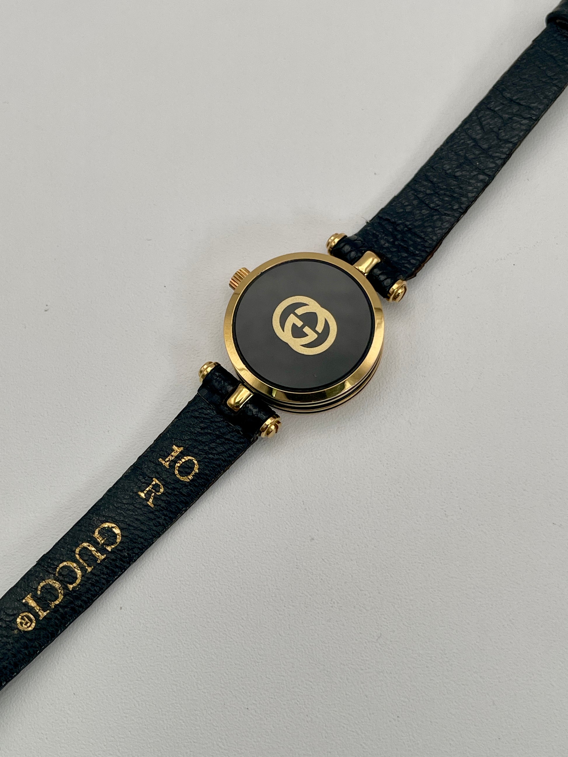 Back view of the Gucci Sherry Line Vintage Women's Watch in gold, featuring the branded caseback and textured black leather strap.