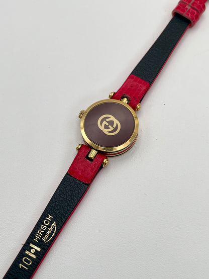 Caseback view of the Gucci watch featuring the brown back cover with gold GG logo and red strap.