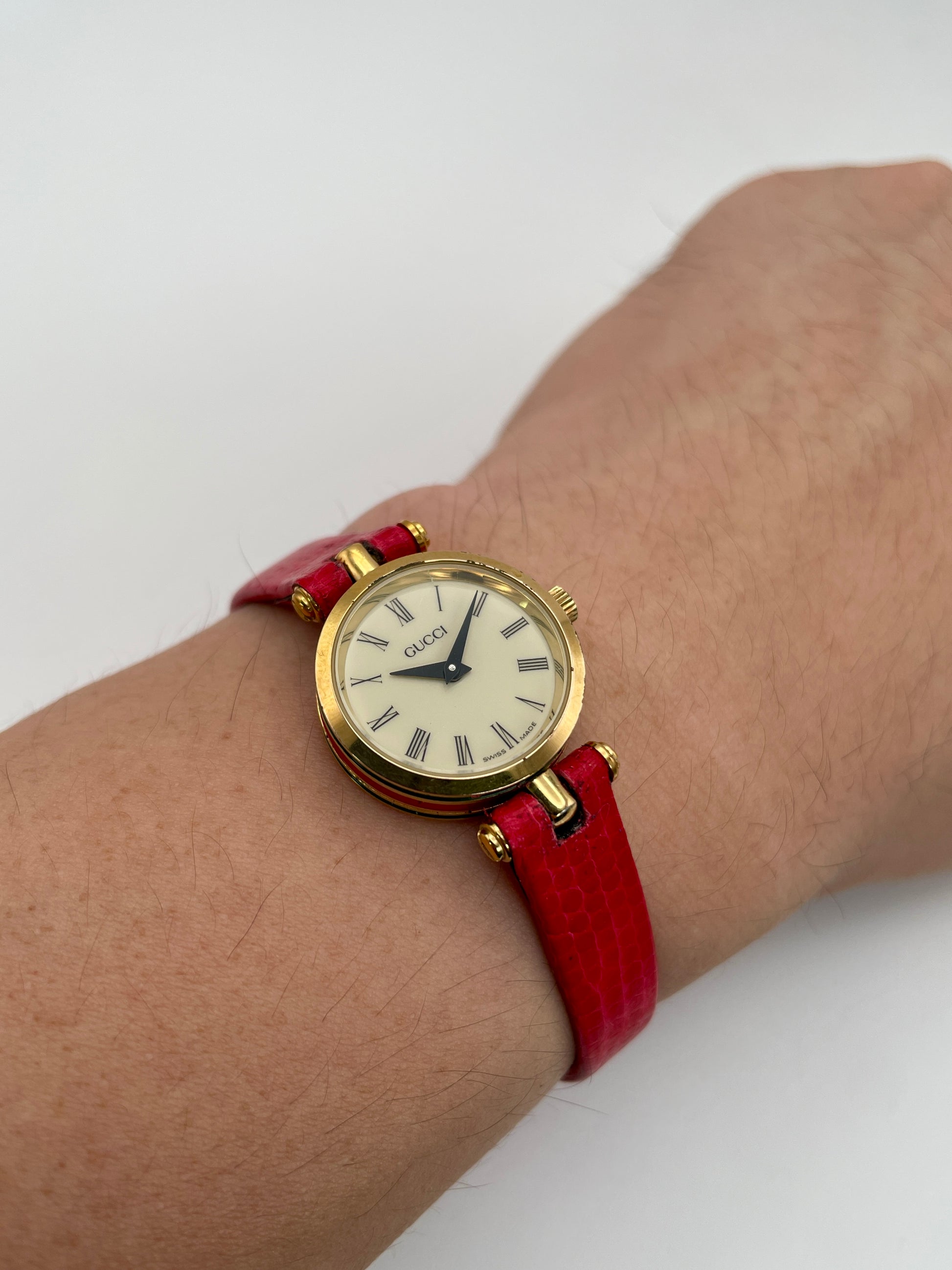 Wrist shot of the Gucci Sherry Line Vintage Watch in gold with red strap, showing how it looks when worn.