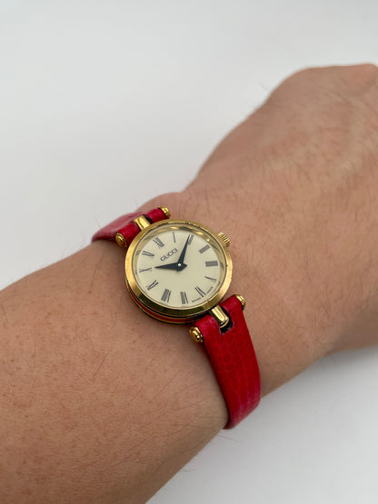 Wrist shot of the Gucci Sherry Line Vintage Watch in gold with red strap, showing how it looks when worn.
