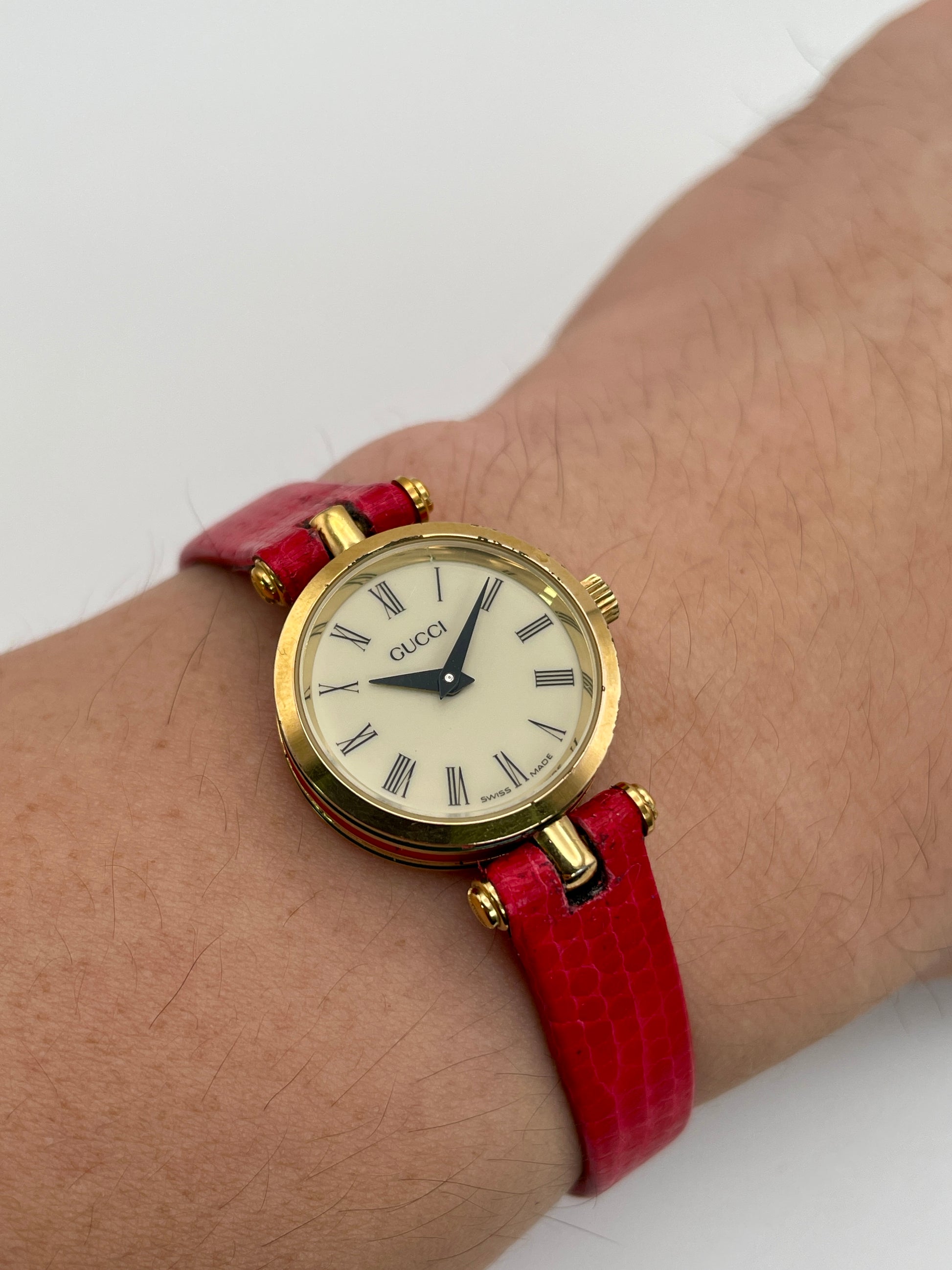 Alternate wrist shot of the Gucci Sherry Line watch in gold and red leather strap, highlighting the dial on wrist.