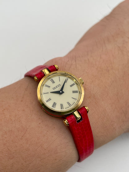 Alternate wrist shot of the Gucci Sherry Line watch in gold and red leather strap, highlighting the dial on wrist.