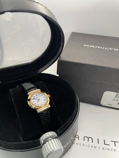 Hamilton 8208 vintage gold watch with a round case, white Roman numeral dial, and black leather strap, shown with original box.