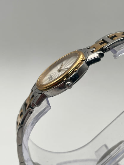 Side view of the Hermès Clipper Oval Vintage Ladies Watch showing the gold bezel and the crown on the stainless steel case.