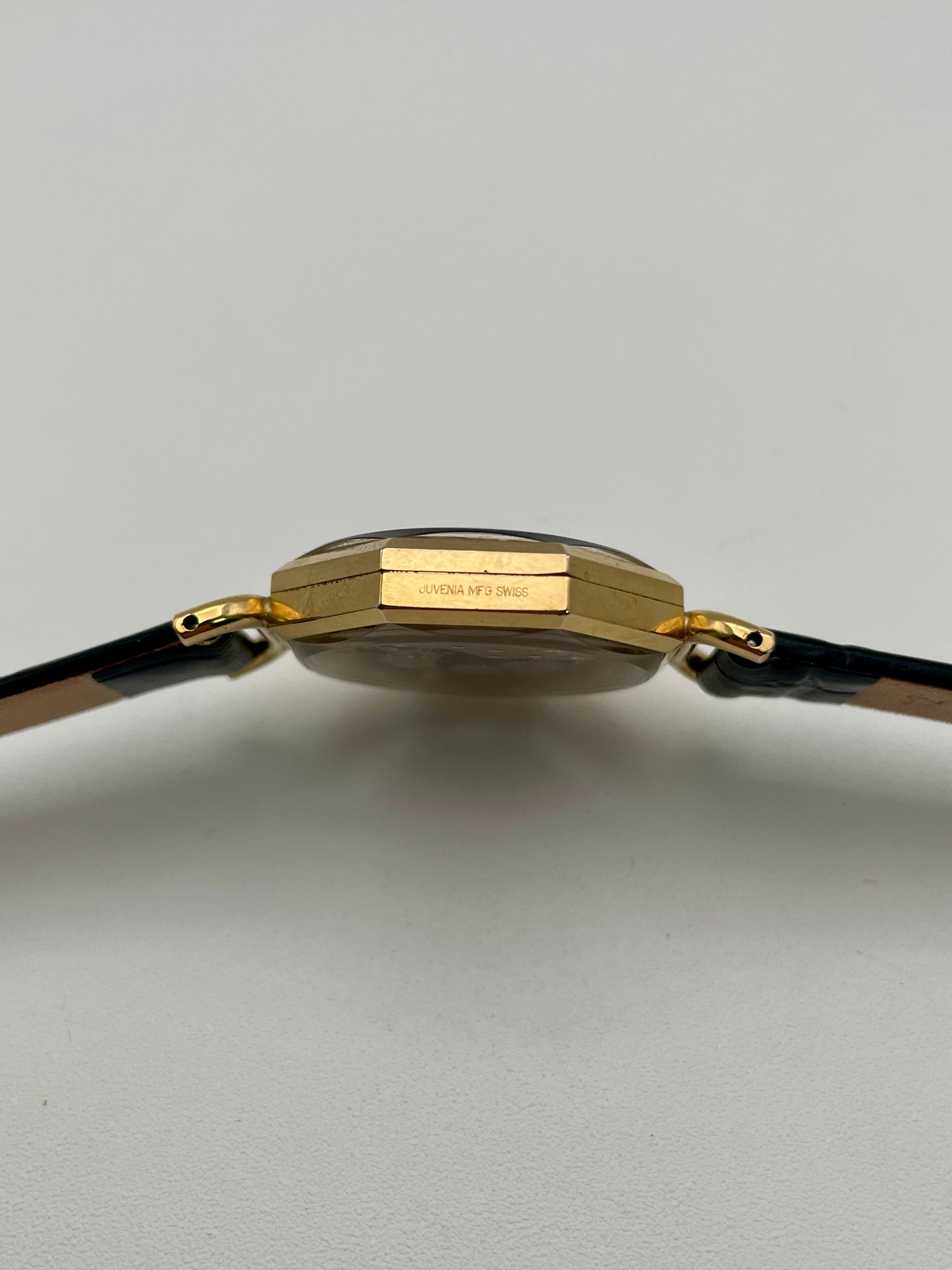 Side profile showing “Juvenia MFG Swiss” engraving on the gold-tone case
