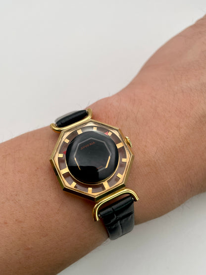 Wrist shot of Juvenia Octagion watch in gold-tone case with black strap, showing size and fit
