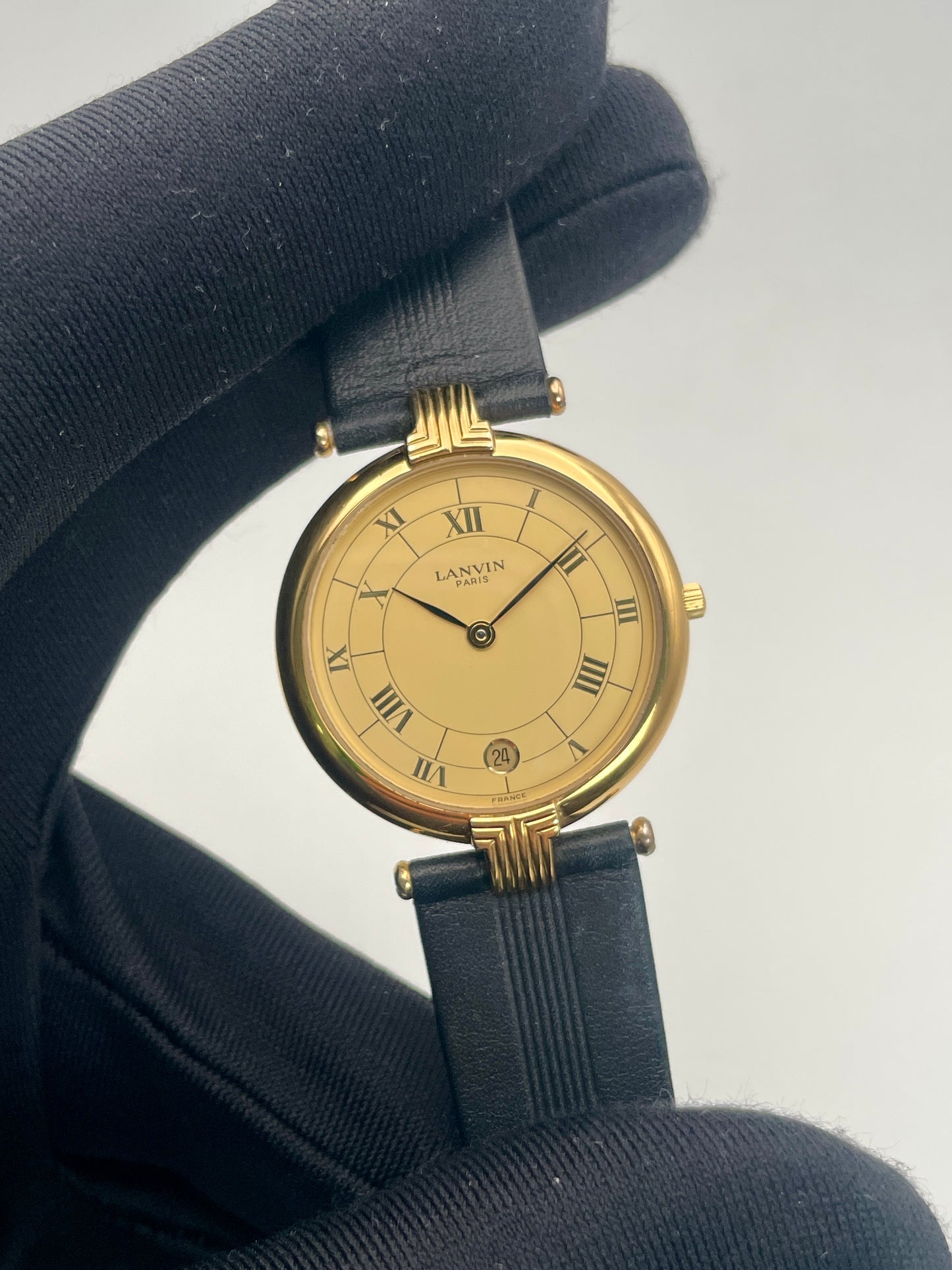 Closeup view of Lanvin Paris Vintage Gold Watch with Roman numeral dial and black strap
