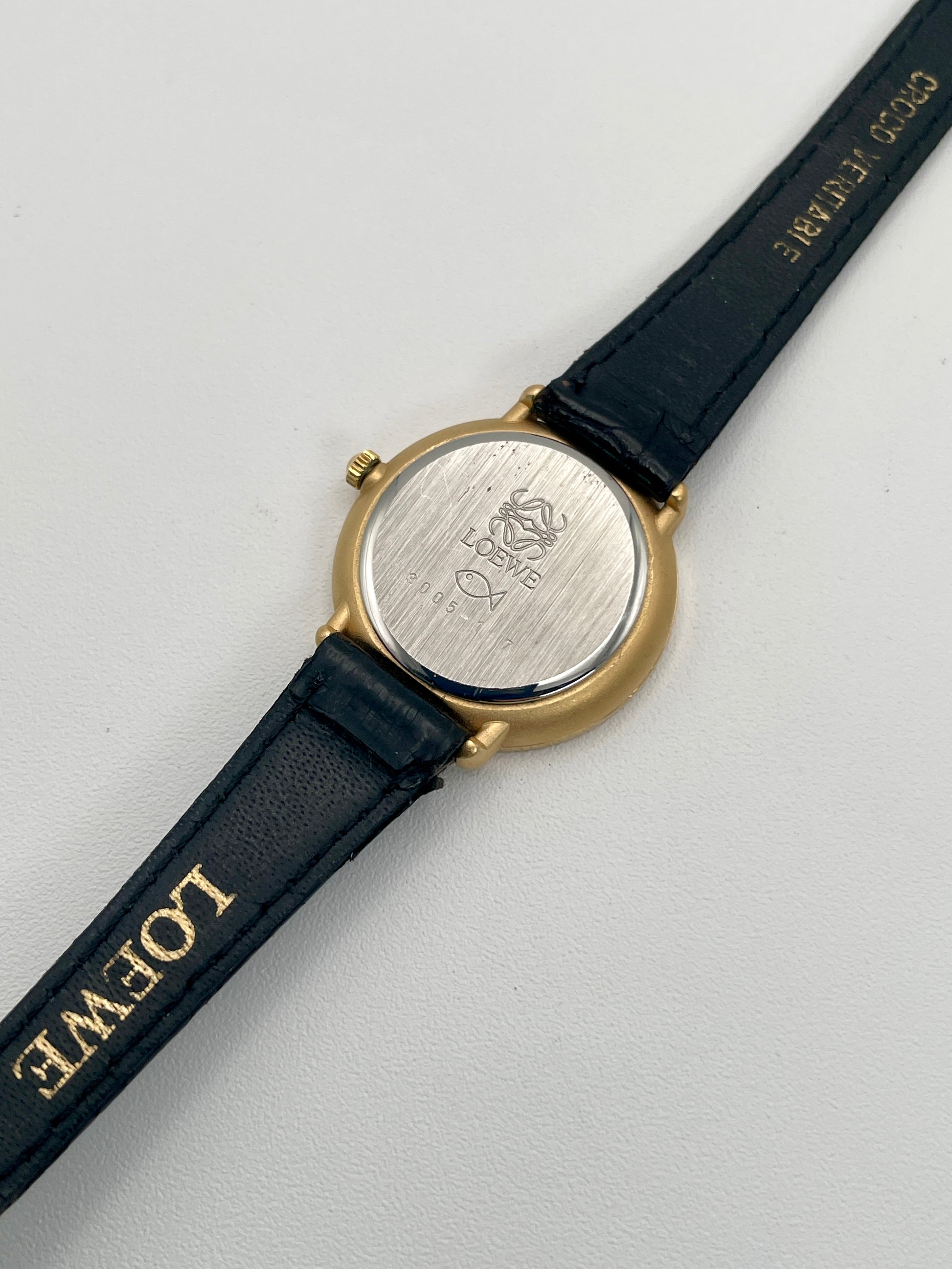 View of the caseback engraved with Loewe branding and fish logo, paired with black leather strap.