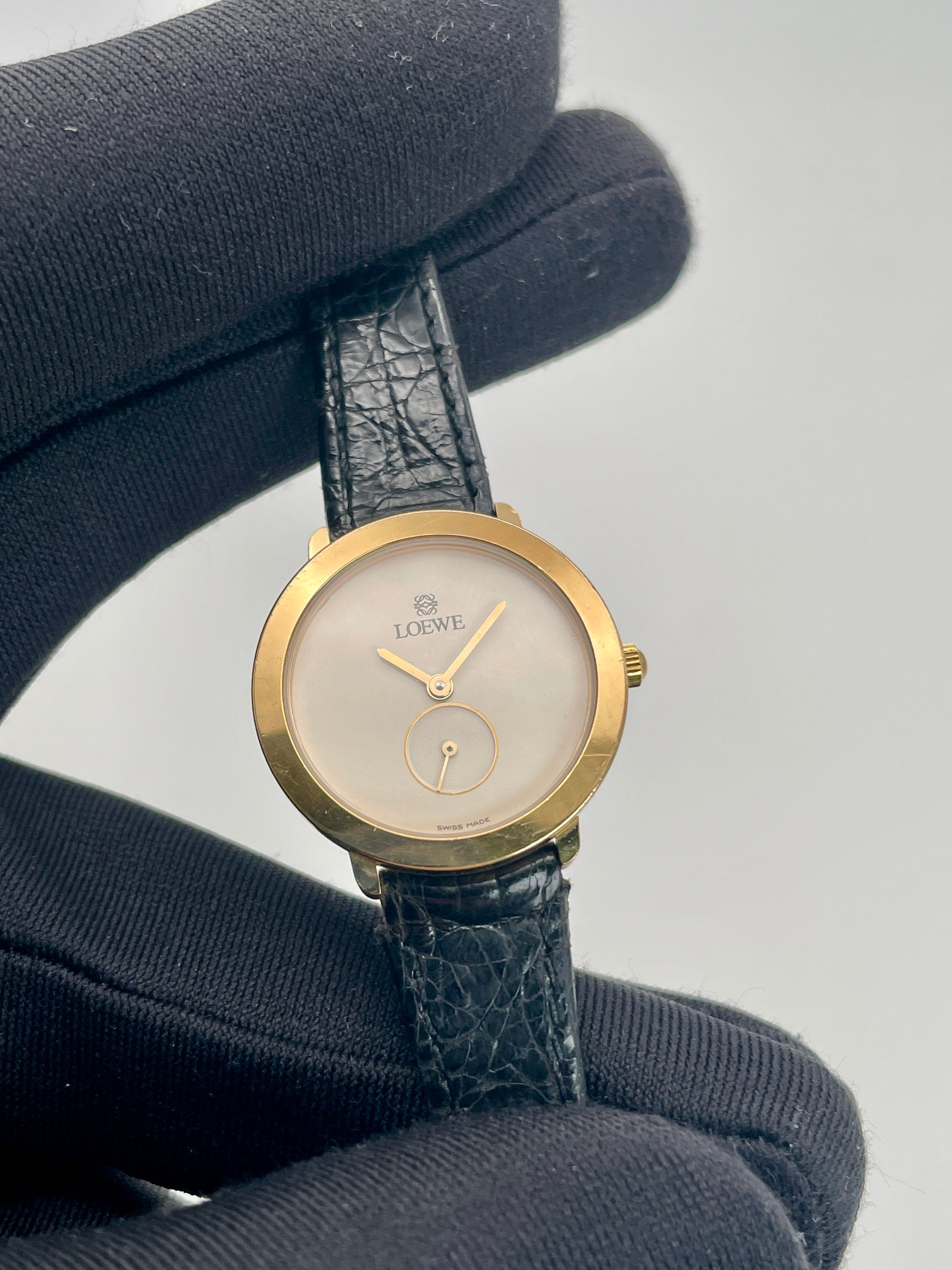 Close-up view highlighting the white dial, sub-seconds circle, and Loewe logo.