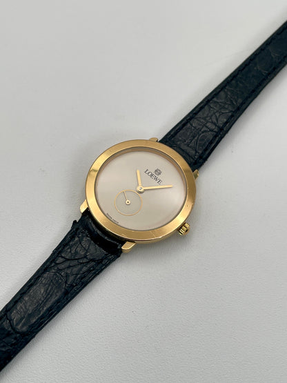 Diagonal view of the Loewe Calatrava gold watch showing the minimal white dial and gold accents.