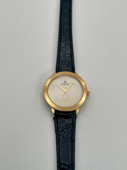 Front view of Loewe Calatrava Vintage Women's Watch in gold case with black leather strap showing white dial and small seconds subdial.