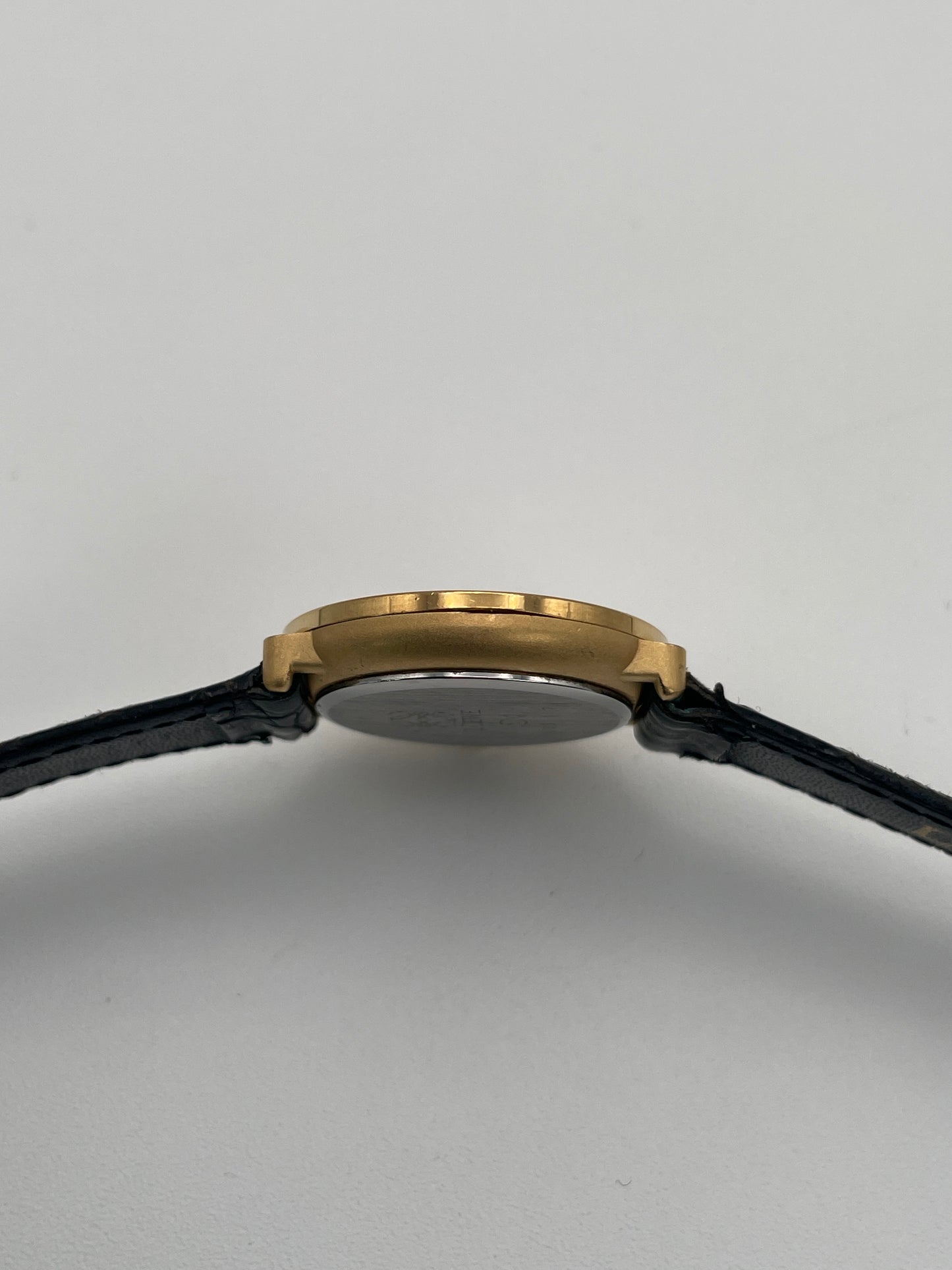 Side profile showcasing the slimness of the gold case and smooth bezel.