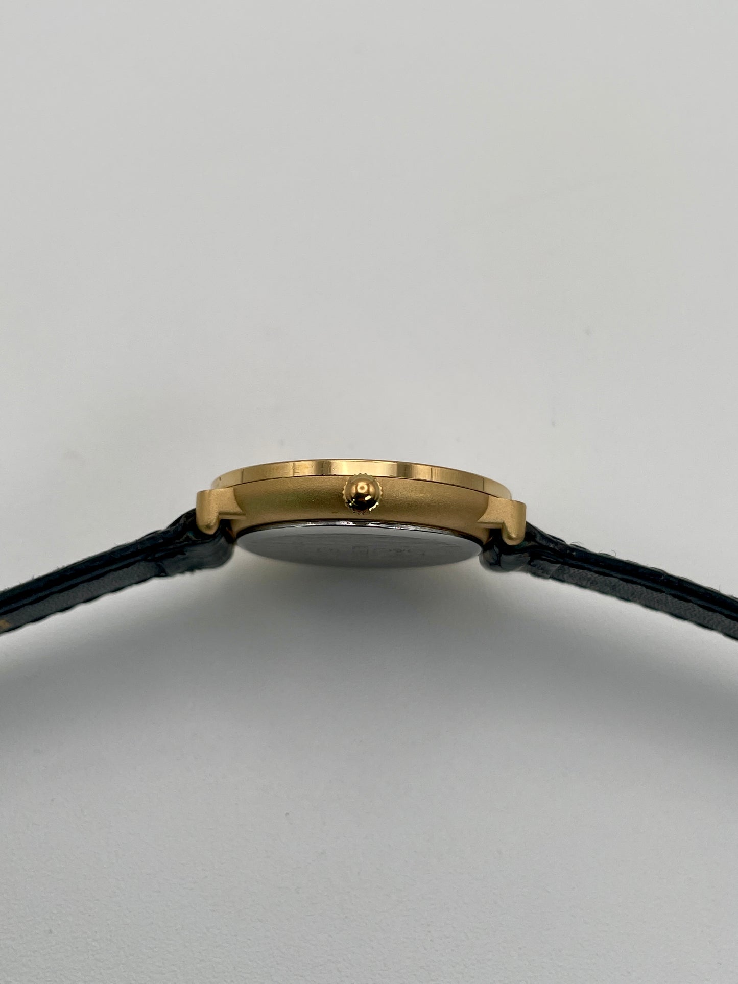 Side view showing the thin gold case and gold crown of the Loewe Calatrava women's watch.