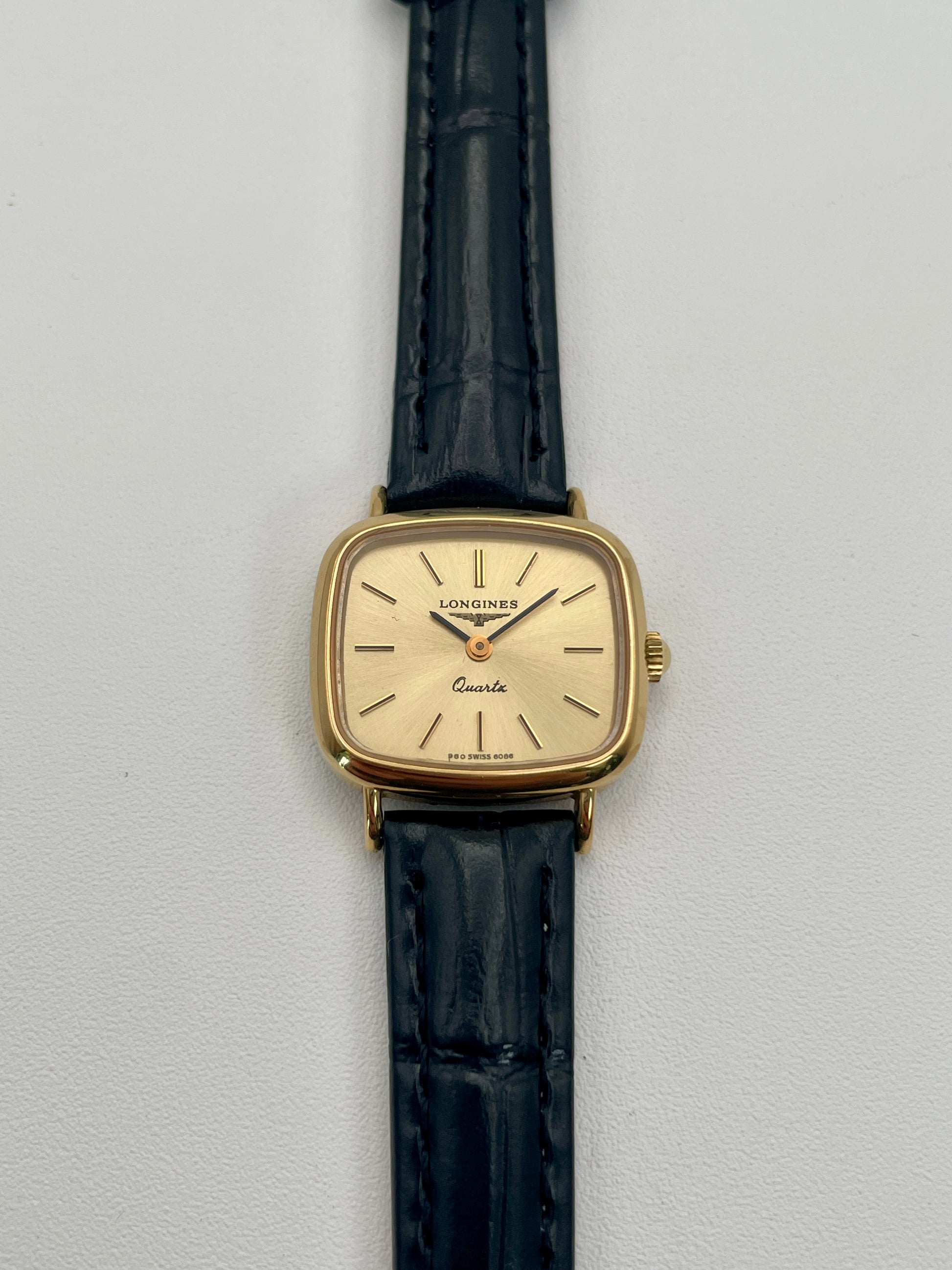 Longines 6068.2 vintage women's watch in gold-tone case with black leather strap, photographed flat from the front
