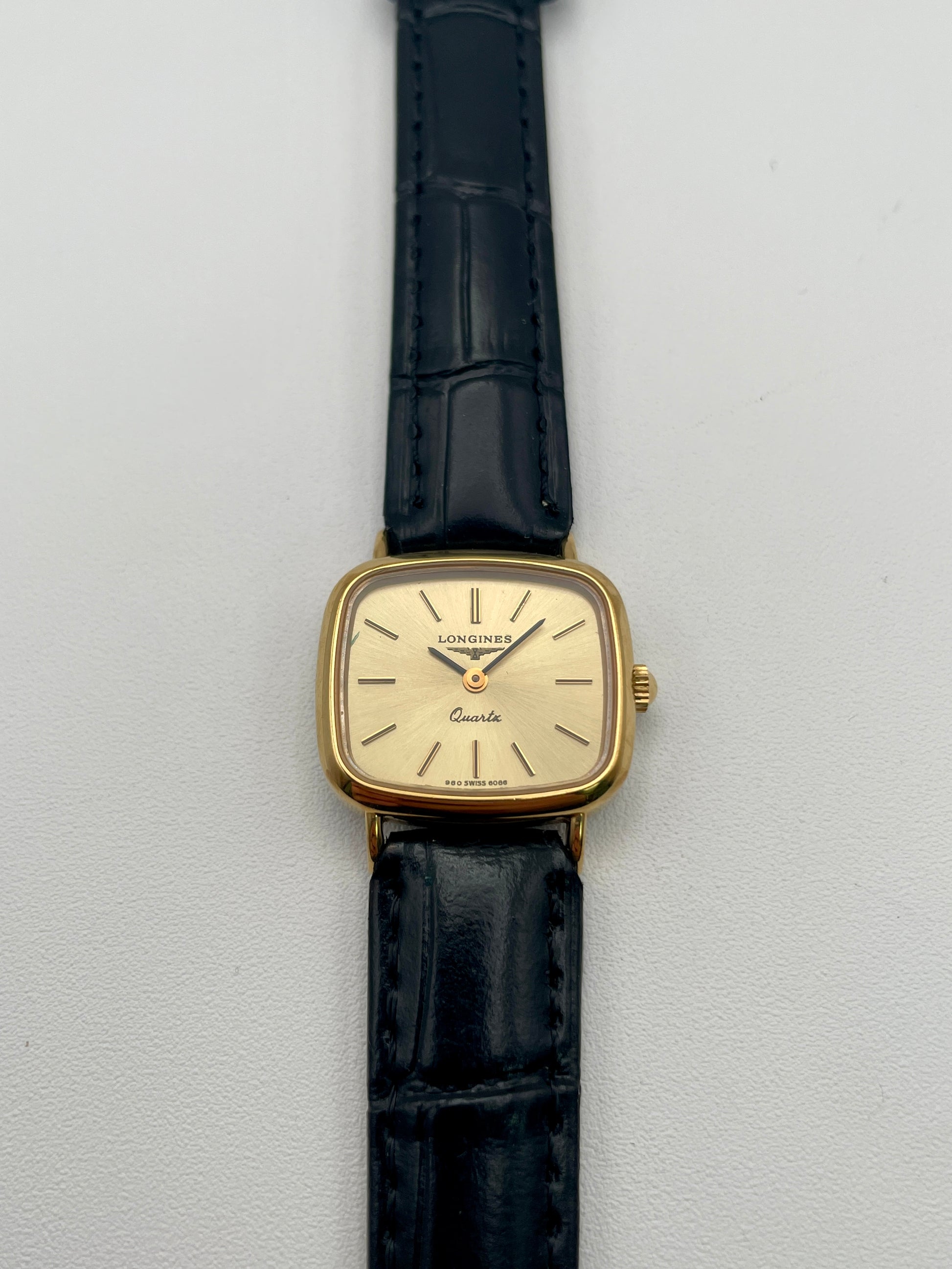 Longines 6068.2 vintage women's watch in gold-tone case with black leather strap, photographed flat from the front
