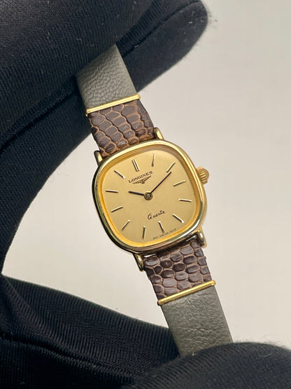 Handheld view of the Longines 960 vintage women's watch, emphasizing the gold-tone dial and leather strap.