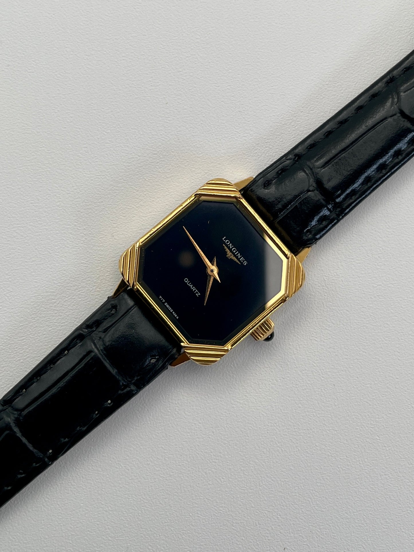 Diagonal view of Longines Neo-Vintage Quartz watch with gold case, black dial, and black leather strap.