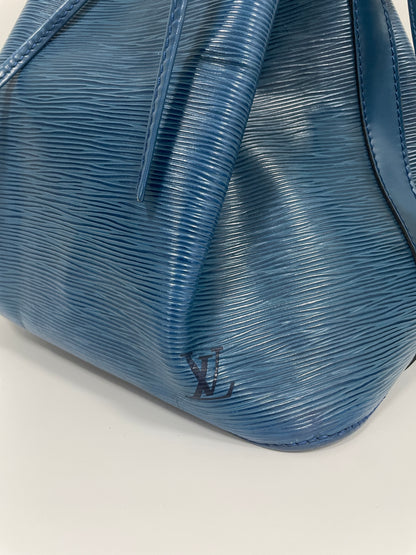 Close-up view of the side of the Louis Vuitton Petit Noé Shoulder Bag in Toledo Blue leather, featuring the embossed LV logo.