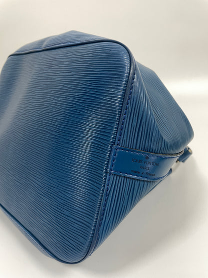 Angled view of the bottom of Louis Vuitton Petit Noé in Toledo Blue Leather, displaying the robust, textured finish and showing the side rib logo.