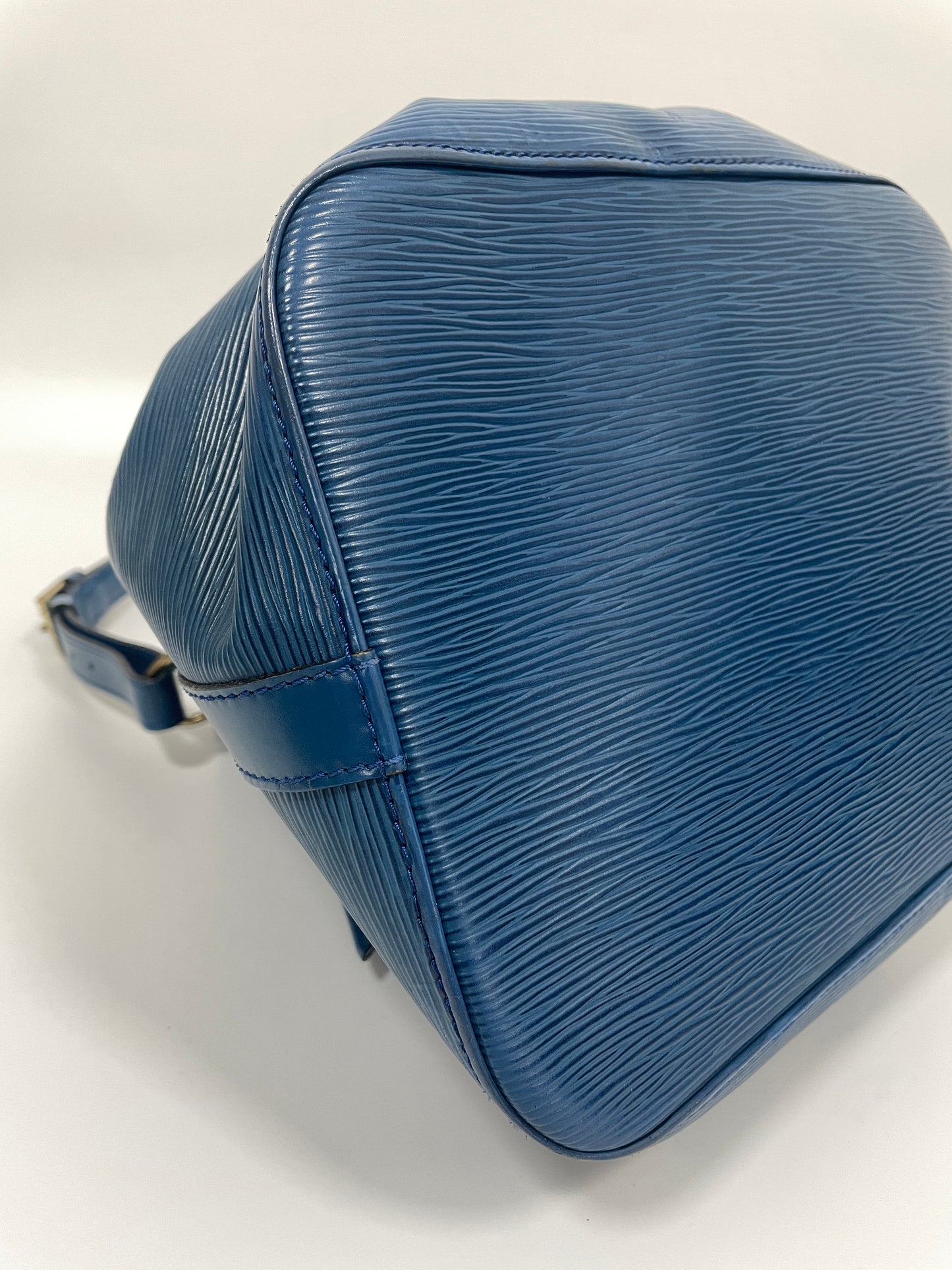 Angled view of the bottom of Louis Vuitton Petit Noé in Toledo Blue Leather, displaying the robust, textured finish.