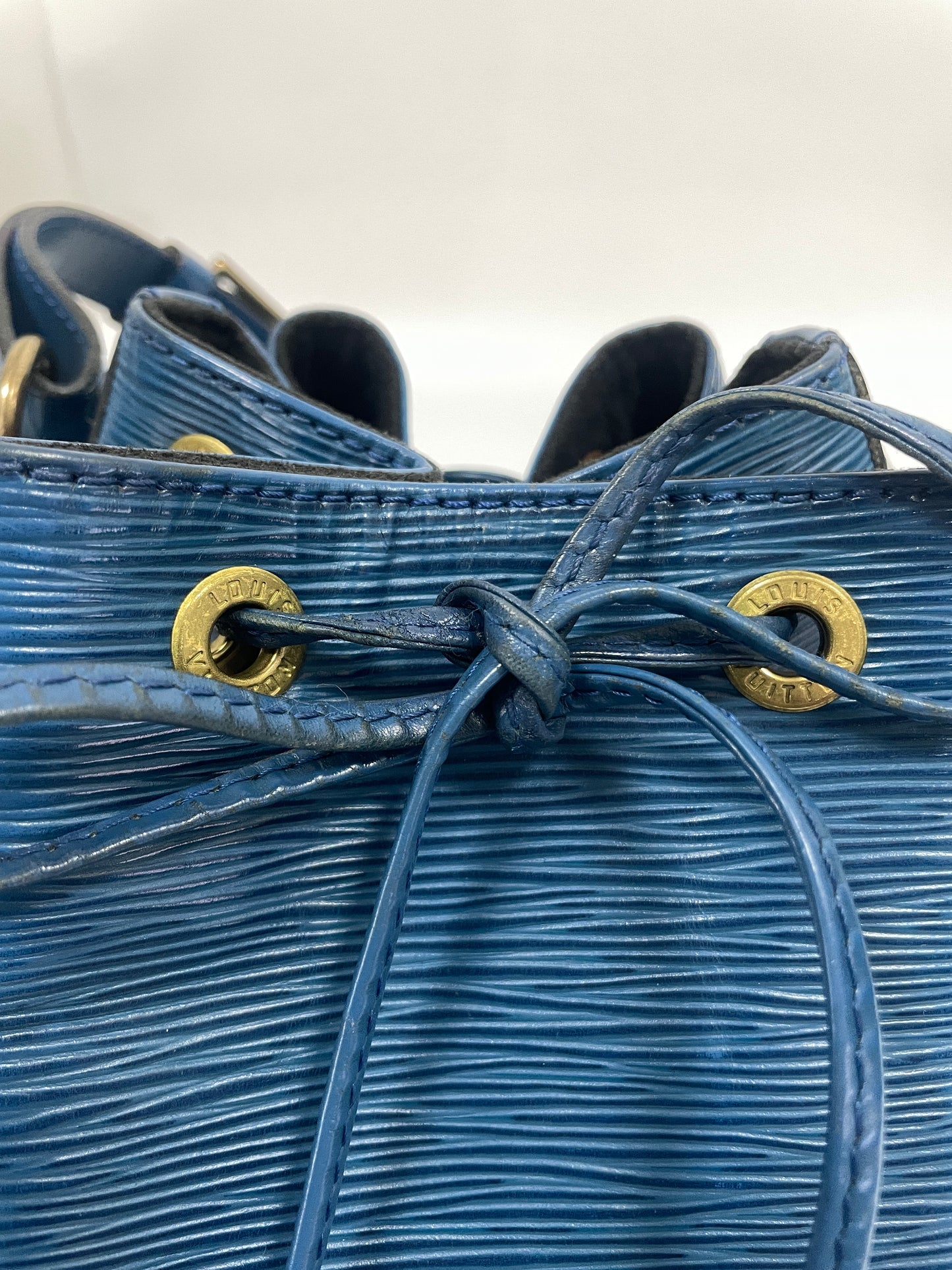 Close-up of the drawstring detail and gold-tone hardware on the Louis Vuitton Petit Noé in Toledo Blue Leather.